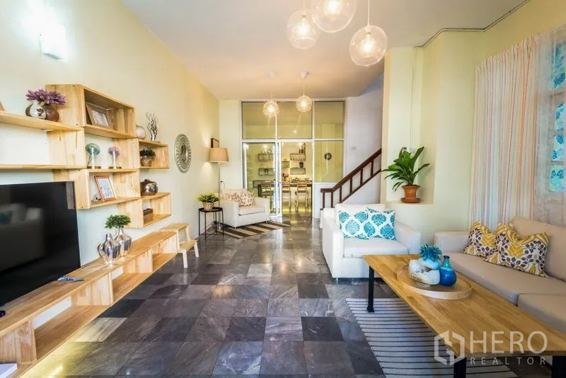 带办公室的家 出租在Suan Luang, Bangkok - 狭长客厅，木质置物架、沙发并通向餐区。