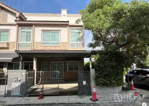 Townhouse for rent in Bang Phli, Samut Prakan - Corner townhouse exterior with gated carport, large tree and modern facade.