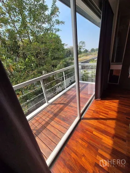 独立式住宅 出租在Bang Kruai, Nonthaburi - 木质阳台配白色栏杆，俯瞰树景。