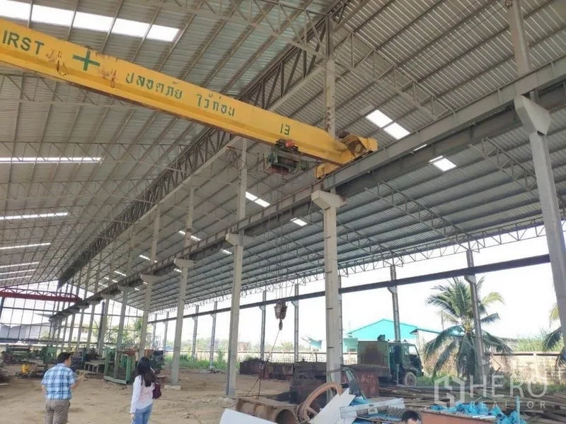 工厂 出租在Samut Sakhon - 仓库内黄色桥式起重机细节，外有棕榈树，Samut Sakhon
