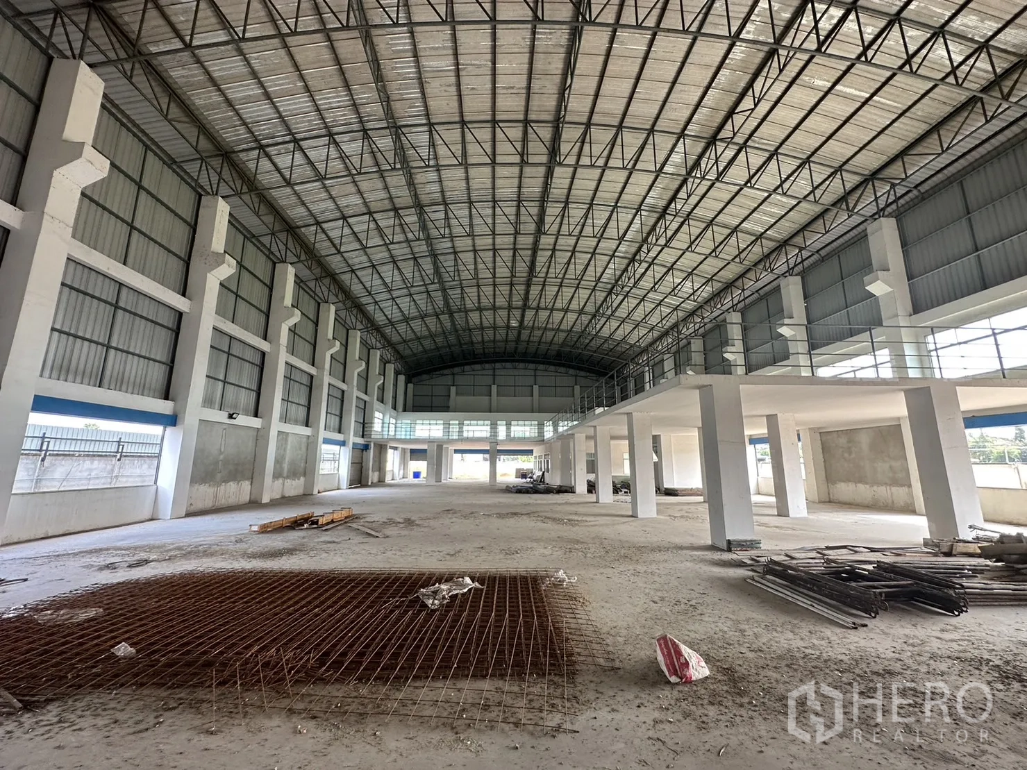 工厂 出租在Pak Kret, Nonthaburi - 室内通道，夹层护栏、侧向卷门与宽阔地面。