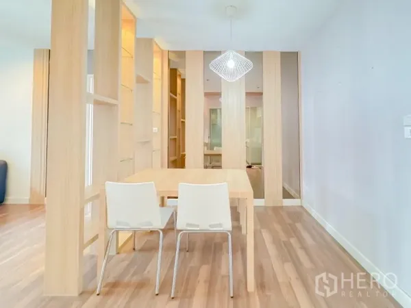 คอนโด ขาย - มุมทานอาหารพร้อมฉากกั้นชั้นไม้ เก้าอี้สีขาวสองตัว และโคมไฟแขวน