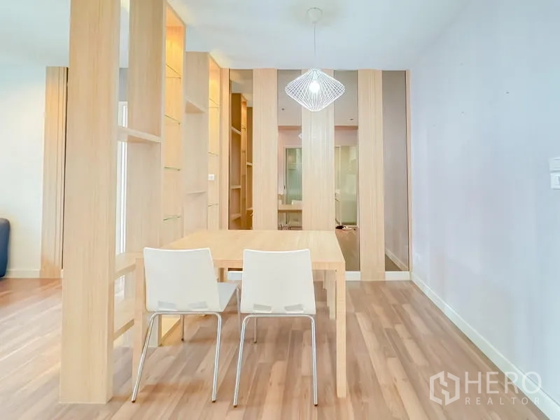 คอนโด ขาย - มุมทานอาหารพร้อมฉากกั้นชั้นไม้ เก้าอี้สีขาวสองตัว และโคมไฟแขวน