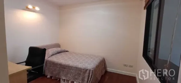 คอนโด ขายในPathum Wan, Bangkok - ห้องนอนรองสไตล์อบอุ่น เตียง โต๊ะทำงาน เก้าอี้ แสงไฟติดผนัง และพื้นไม้ ในคอนโดกรุงเทพฯ