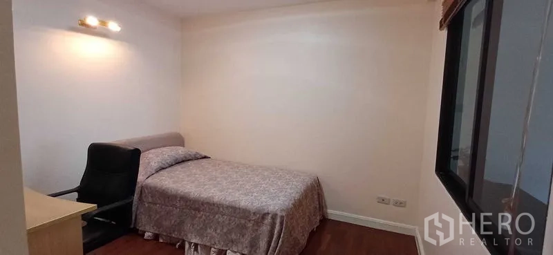 คอนโด ขายในPathum Wan, Bangkok - ห้องนอนรองสไตล์อบอุ่น เตียง โต๊ะทำงาน เก้าอี้ แสงไฟติดผนัง และพื้นไม้ ในคอนโดกรุงเทพฯ