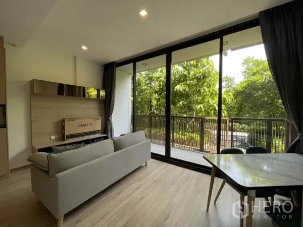 คอนโด ขายในWatthana, Bangkok - มุมห้องนั่งเล่นพร้อมประตูกระจกบานเลื่อนออกสู่ระเบียงและวิวสวนร่มรื่น