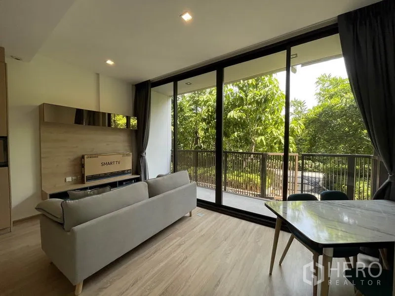คอนโด ขายในWatthana, Bangkok - มุมห้องนั่งเล่นพร้อมประตูกระจกบานเลื่อนออกสู่ระเบียงและวิวสวนร่มรื่น