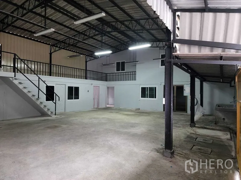 货栈 出租在Chatuchak, Bangkok - 整跨室内空间，钢结构屋顶与明亮灯具，侧边夹层一览。