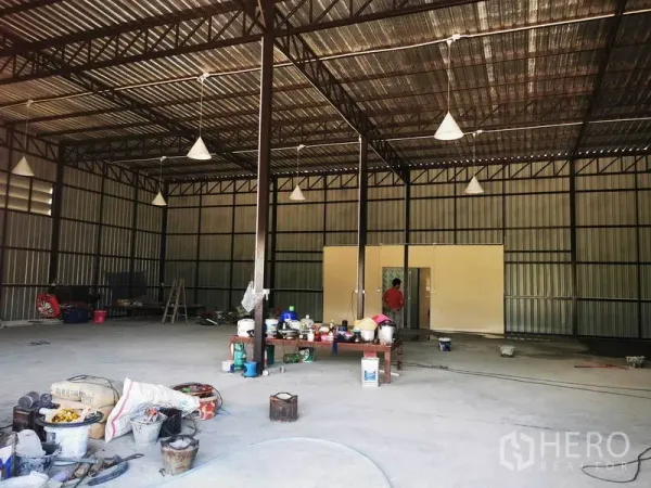 Warehouse for rent - Central view of the warehouse showing steel columns, high roof and a doorway to utility rooms.