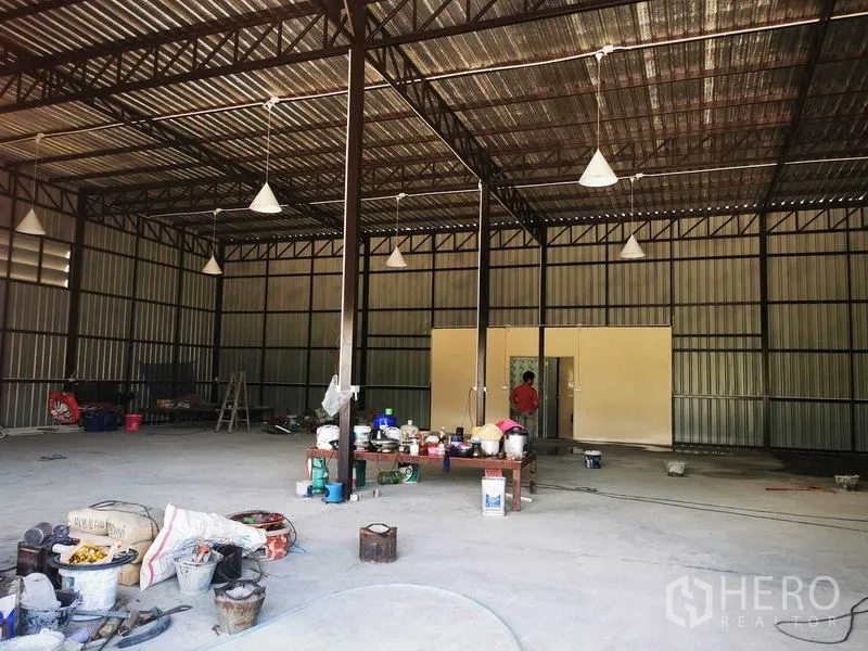 Warehouse for rent - Central view of the warehouse showing steel columns, high roof and a doorway to utility rooms.