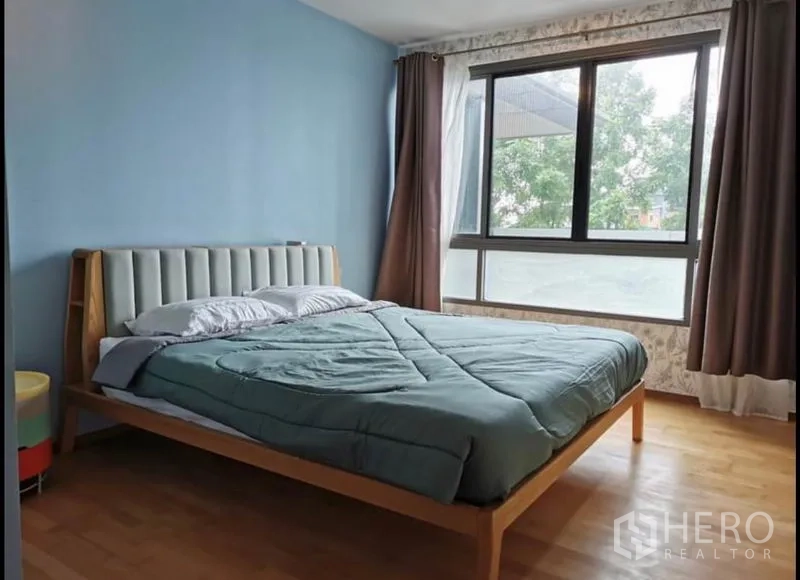 คอนโด ให้เช่าในKhlong Toei, Bangkok - ห้องนอนใหญ่พร้อมหน้าต่างบานกว้าง ผนังสีฟ้า และวิวสวน