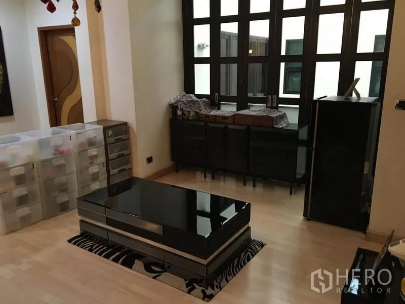 Detached House for rent in Khlong Toei, Bangkok - Family lounge with black lacquer coffee table and cabinetry by tall windows.