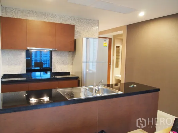 คอนโด ให้เช่าหรือขายในWatthana, Bangkok - ครัวสมัยใหม่ เคาน์เตอร์หินแกรนิตสีดำ อ่างล้างจานบนไอแลนด์ และตู้เย็นสแตนเลส