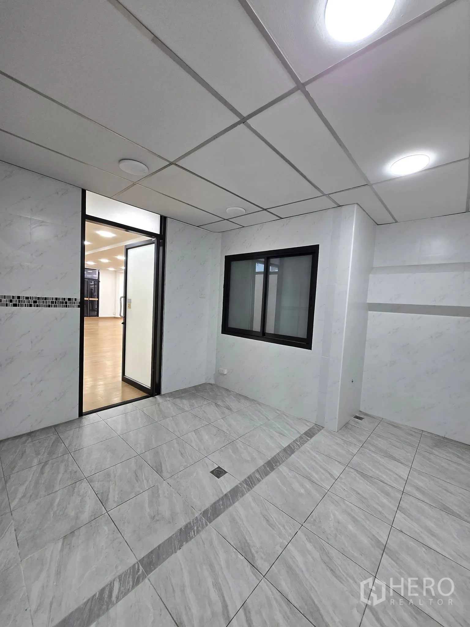 Office Space for rent in Khlong Toei, Bangkok - Tiled room with recessed lights, a window to the office, and a glass door to the open area.