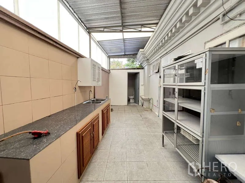 Detached House for rent in Bang Phli, Samut Prakan - Covered Thai kitchen and utility area with long granite counter, sink, and storage.