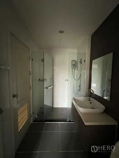 Townhouse for rent in Bang Kapi, Bangkok - Bathroom with glass shower screen, vanity and dark feature wall.