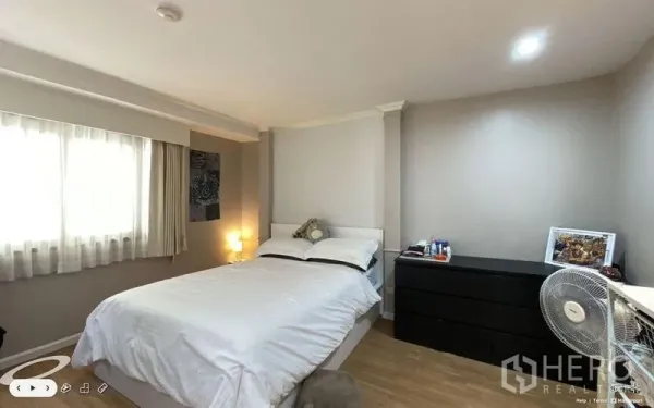 Condominium for sale in Watthana, Bangkok - Bright bedroom with double bed, curtained window and black dresser.