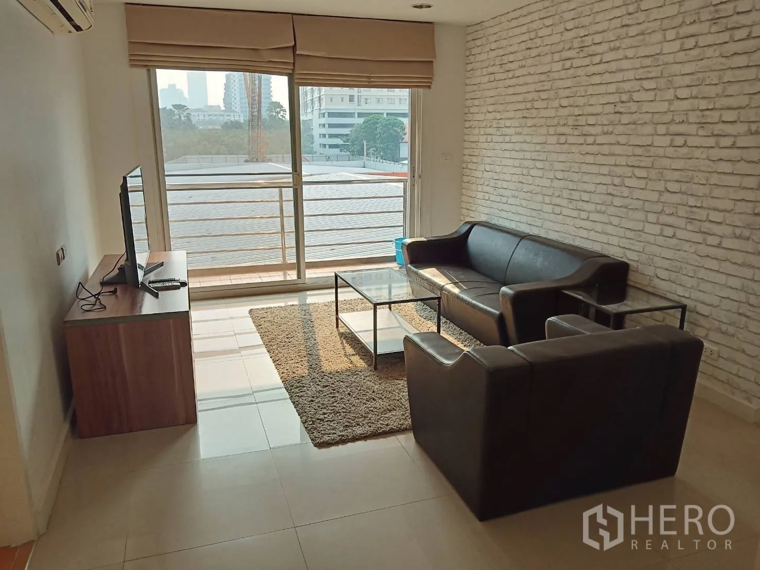 คอนโด ให้เช่าหรือขายในKhlong Toei, Bangkok - ห้องนั่งเล่นโซฟาหนังสีดำ โต๊ะกลางกระจก และประตูระเบียงบานเลื่อน