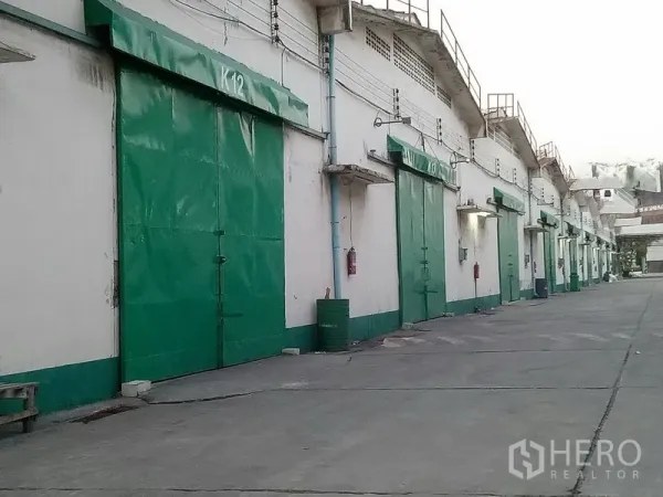 货栈 出租在Khlong Toei, Bangkok - 靠服务通道的绿色金属仓库门与管线设施的近景。