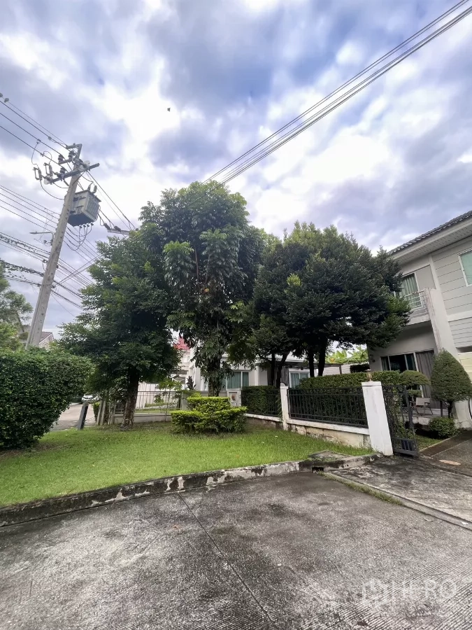 บ้าน ขายในMin Buri, Bangkok - มุมมองหน้าบ้านและสนามหญ้า พร้อมต้นไม้ใหญ่และสายไฟริมถนน