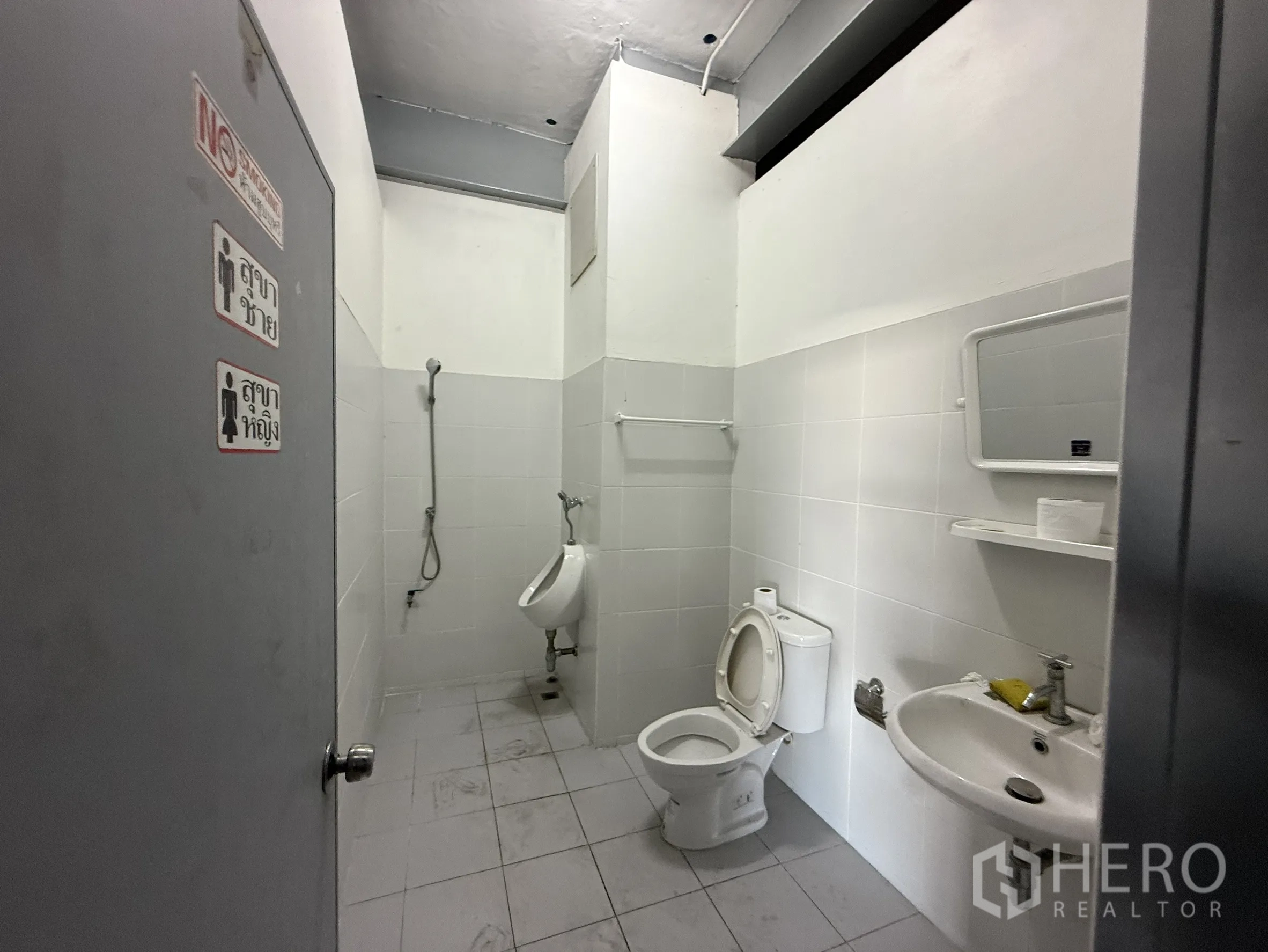 Warehouse for rent in Bueng Kum, Bangkok - Restroom with toilet, urinal, sink, and handheld shower.