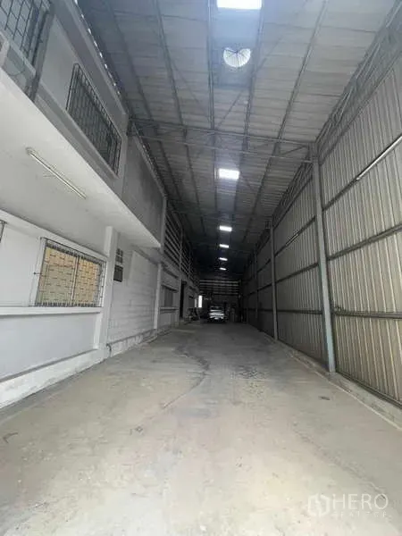 Warehouse for rent in Lam Luk Ka, Pathum Thani - Covered loading corridor inside the warehouse with high metal walls, skylights, and a concrete floor in Lam Luk Ka.