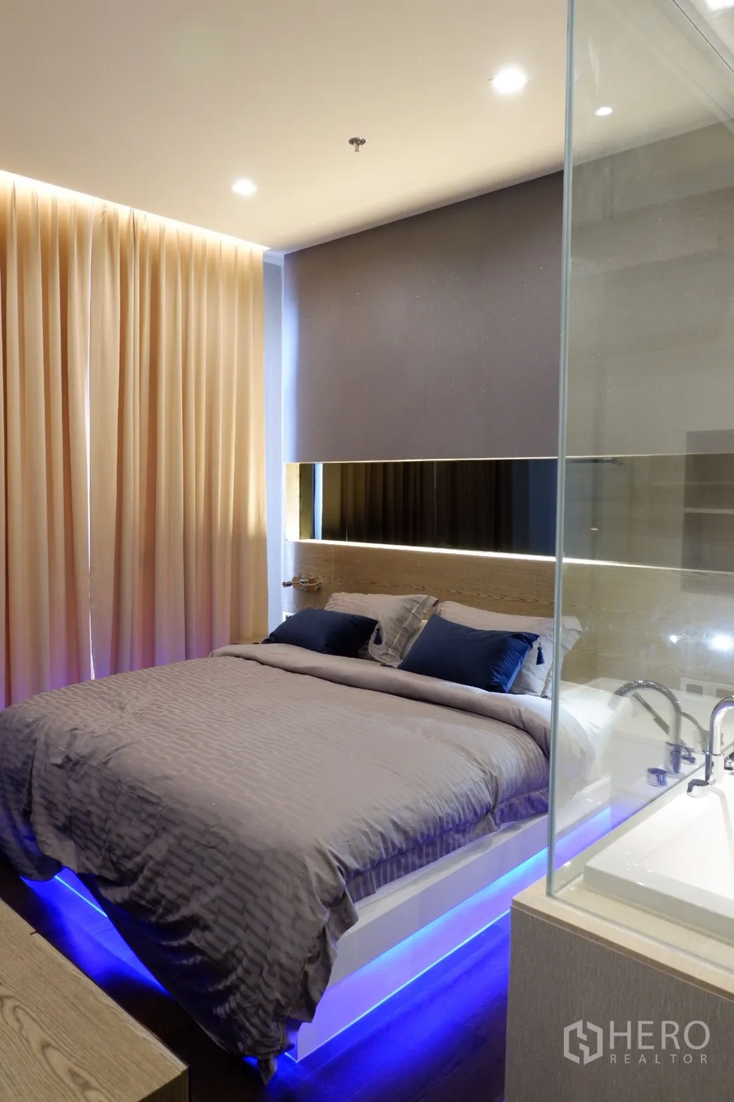 Condominium for rent in Watthana, Bangkok - Bright bedroom with queen bed, soft curtains and blue LED under-bed lighting next to a glass-panel bathroom.