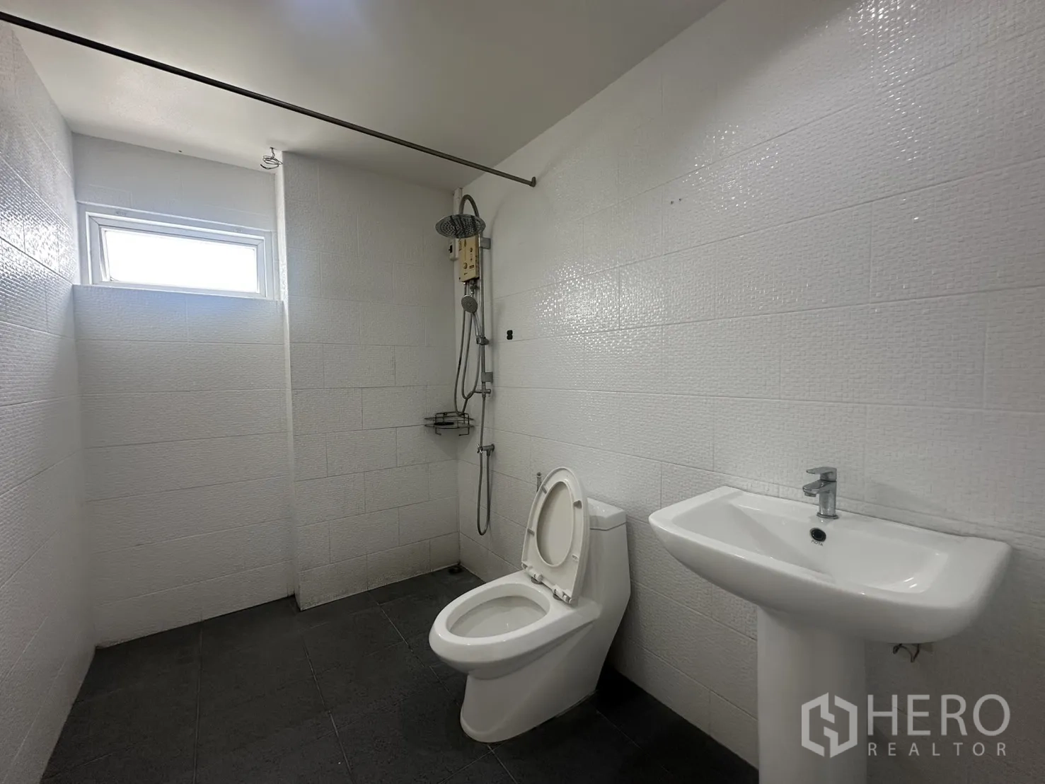 Home Office for rent in Watthana, Bangkok - Bathroom with shower, toilet, and pedestal sink in white tile.