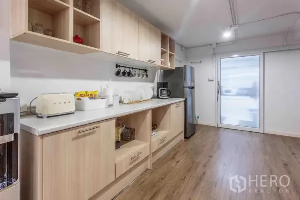 Townhouse for rent in Bang Rak, Bangkok - Pantry with light wood cabinets, open shelves, and a stainless refrigerator.