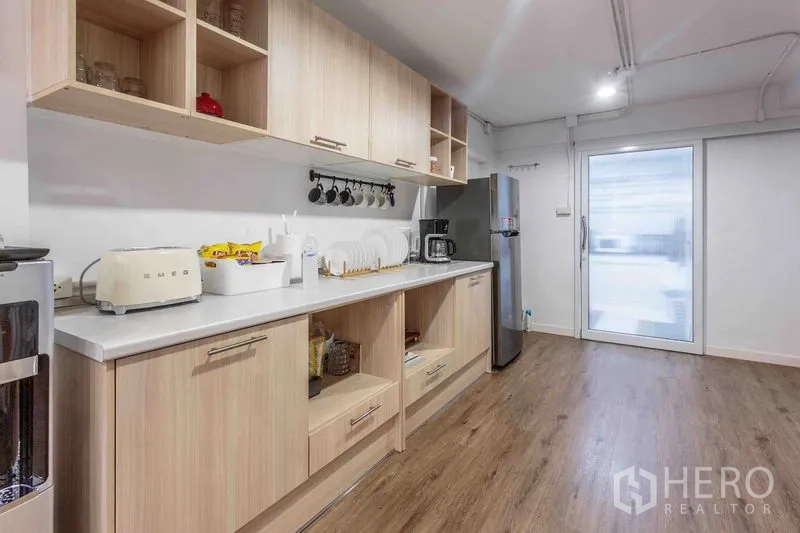 Townhouse for rent in Bang Rak, Bangkok - Pantry with light wood cabinets, open shelves, and a stainless refrigerator.