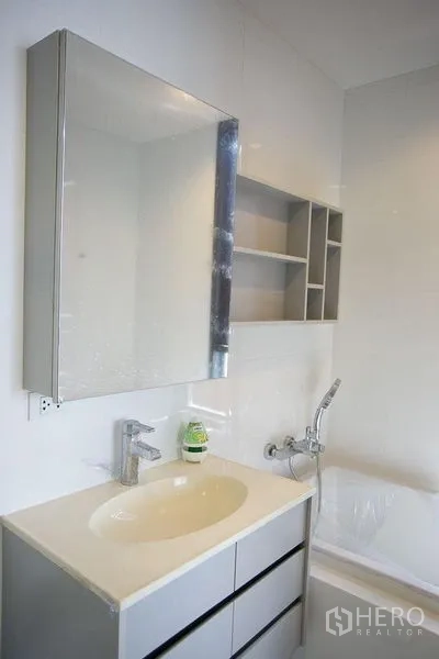 公寓 出租在Watthana, Bangkok - 卫浴配镜柜、开放格架与浴缸出水口的洗浴区。