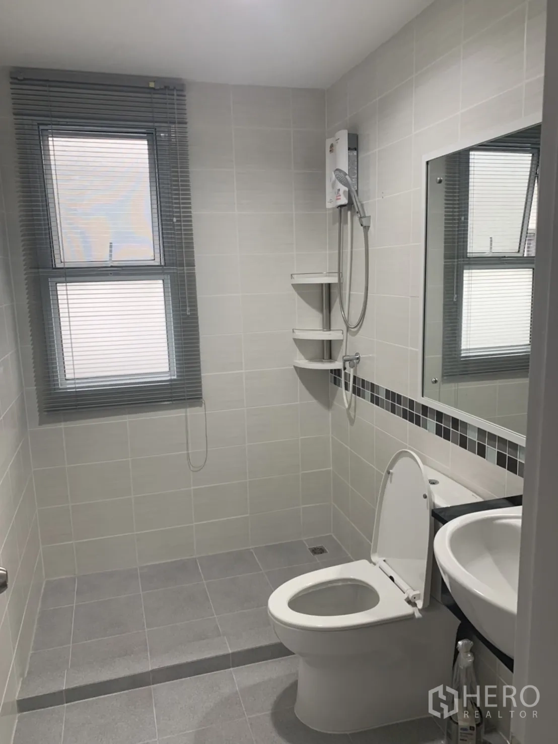 联排别墅 for rent in Bang Kapi, Bangkok - 瓷砖卫浴，坐便器、洗手盆、镜子、百叶窗，以及带热水器的淋浴间。