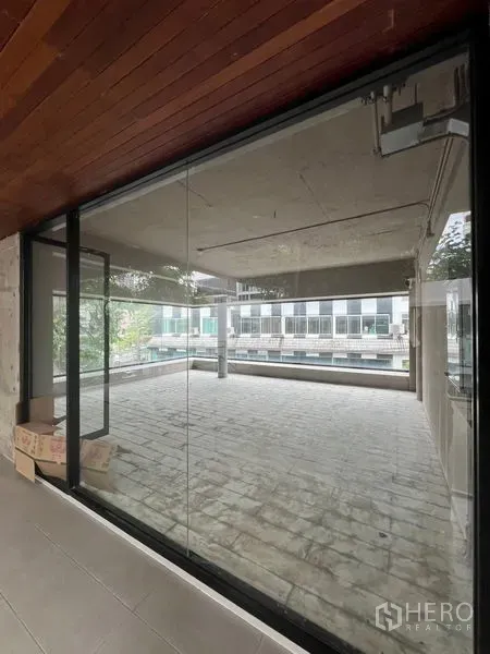 Retail Space for rent in Watthana, Bangkok - Glass entry revealing bright retail floor with expansive corner glazing.