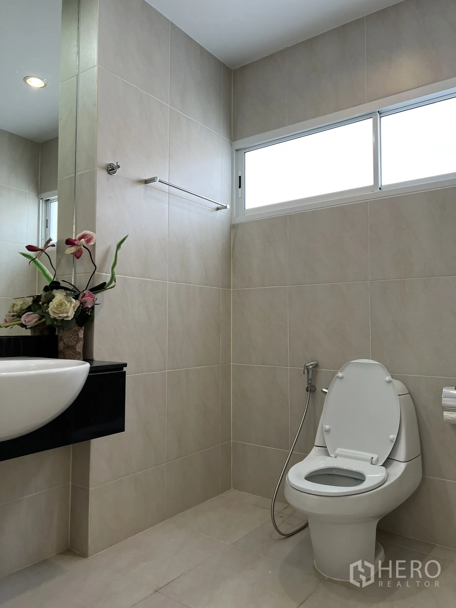 บ้าน ให้เช่าหรือขายในSaphan Sung, Bangkok - ห้องน้ำกระเบื้องสีเบจ อ่างล้างหน้าแขวนผนังและโถสุขภัณฑ์ ใต้หน้าต่างสูง