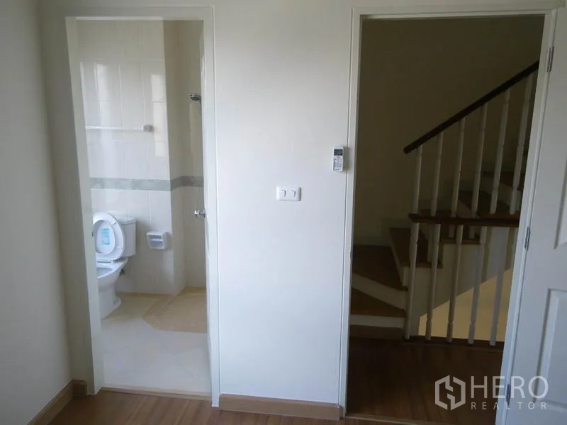 带办公室的家 出租或出售在Suan Luang, Bangkok - 明亮的过道，带通往瓷砖卫生间的门与旁边的木楼梯。