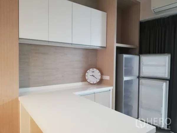 Townhouse for rent in Bang Kapi, Bangkok - Pantry area with white overhead cabinets, light wood finishes and a double-door refrigerator.