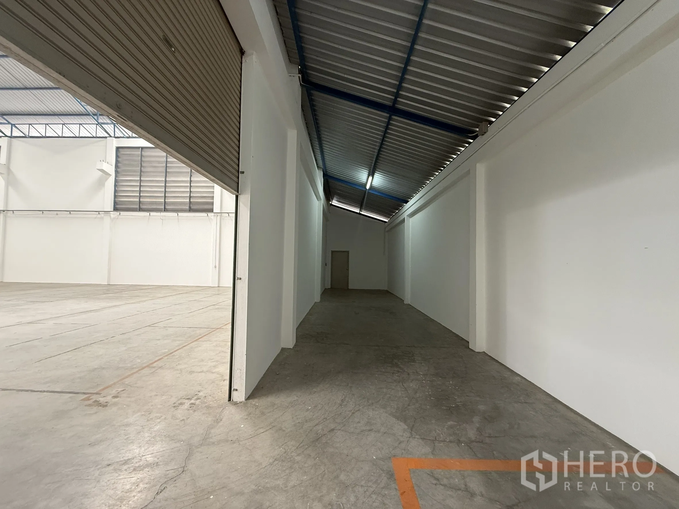 Warehouse for rent or sale in Bang Bo, Samut Prakan - Side service aisle inside the warehouse next to a roller shutter opening.