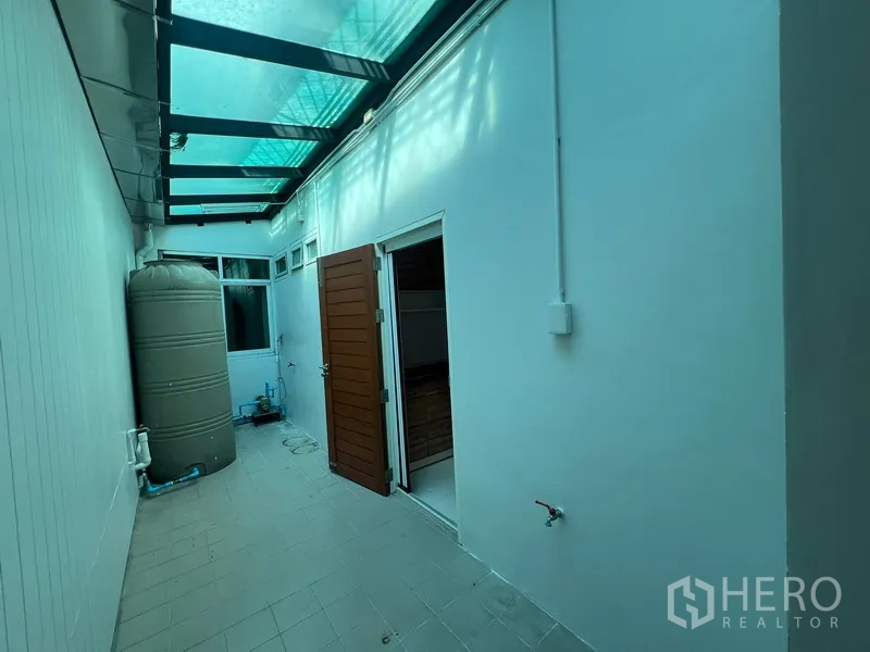 Townhouse for rent in Din Daeng, Bangkok - Rear utility courtyard with translucent roof, water tank and side door access.