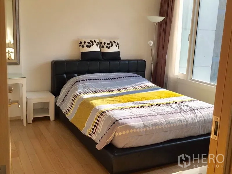 คอนโด ให้เช่าในKhlong Toei, Bangkok - ห้องนอนอบอุ่น เตียงหัวบุผ้า โต๊ะข้าง และหน้าต่างมุมรับแสง.