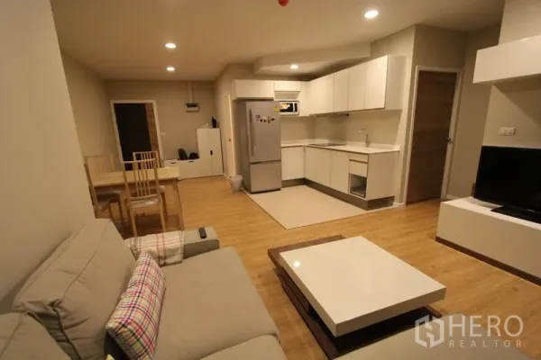 公寓 出租在Pathum Wan, Bangkok - 开放式客餐厅，配沙发、餐桌与白色L形厨房。