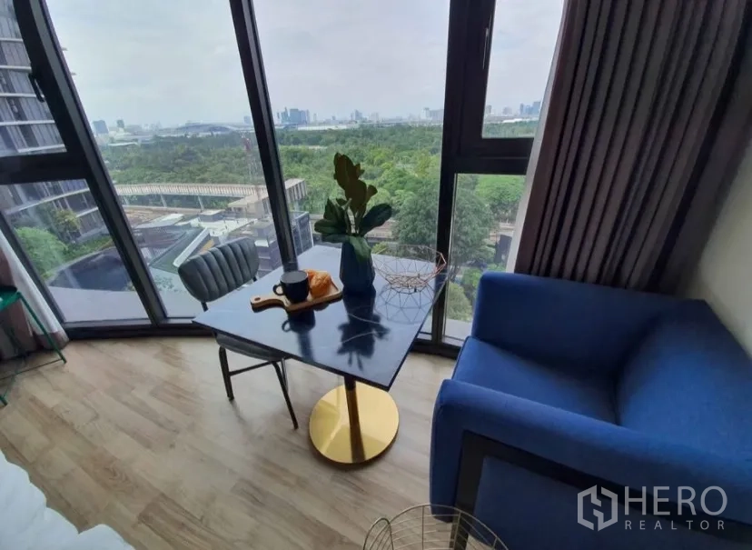 Condominium for rent in Chatuchak, Bangkok - Corner seating area by panoramic windows with a small table and armchair.