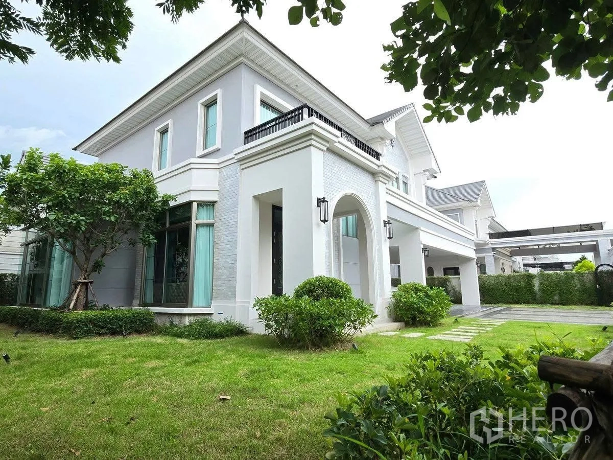 Detached House for rent or sale in Bang Phli, Samut Prakan - Two-storey detached house exterior with white facade, arched porch, lawn and mature landscaping.
