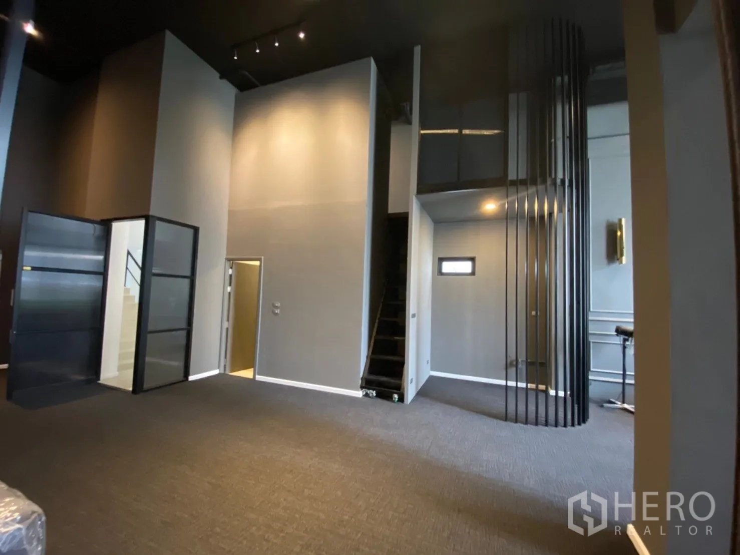 Home Office for rent or sale in Watthana, Bangkok - Double‑height workspace featuring a staircase, glass doors, and an industrial black ceiling.