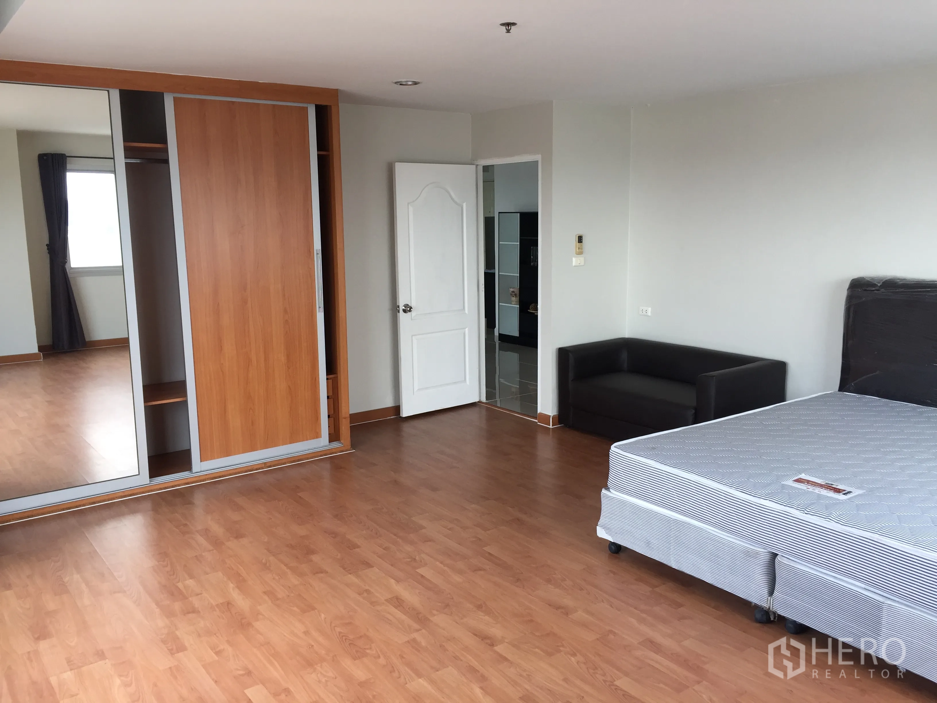 คอนโด ให้เช่าในKhlong Toei, Bangkok - ห้องนอนกว้าง ปูพื้นไม้ ตู้เสื้อผ้าบานเลื่อนกระจก และโซฟาขนาดเล็ก