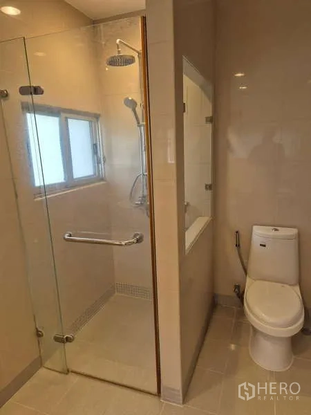 独立式住宅 出租在Bang Kruai, Nonthaburi - 浴室设玻璃淋浴间与现代坐便器。