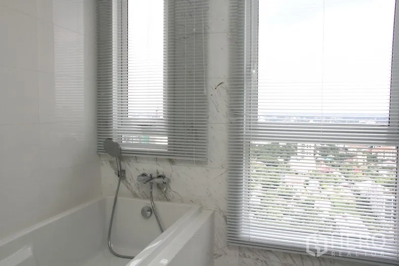 คอนโด ให้เช่าหรือขายในWatthana, Bangkok - ห้องน้ำพร้อมอ่างอาบน้ำ ผนังลายหินอ่อน และหน้าต่างบานใหญ่พร้อมมู่ลี่มองเห็นเมือง