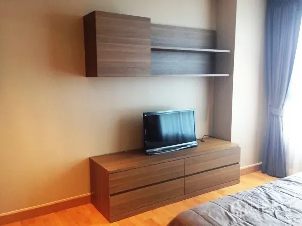 Condominium for rent or sale in Mueang Samut Prakan, Samut Prakan - Built-in TV cabinet with floating shelves in the bedroom beside curtained window.