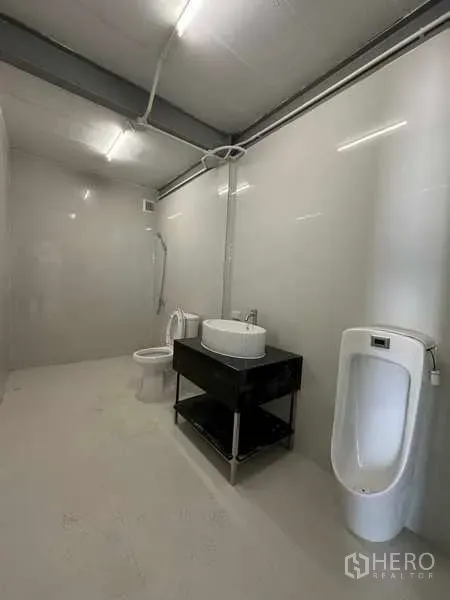 工厂 出租在Wang Noi, Phra Nakhon Si Ayutthaya - 厂内整洁卫生间，配备坐便器、小便斗和洗手台，照明明亮。