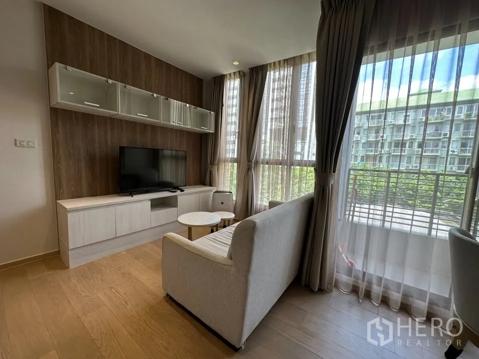 公寓 for rent in Watthana, Bangkok - 转角客厅配大面积落地窗和阳台，视野城市与绿景相映。