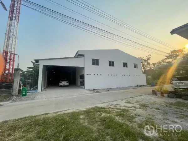 คลังสินค้า ขายในLam Luk Ka, Pathum Thani - มุมมองด้านหน้าโกดังสีขาว ถนนกว้าง ที่จอดรถหน้าบ้าน บรรยากาศยามเย็น